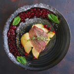 Top view of duck breast with apple and currant sauce
